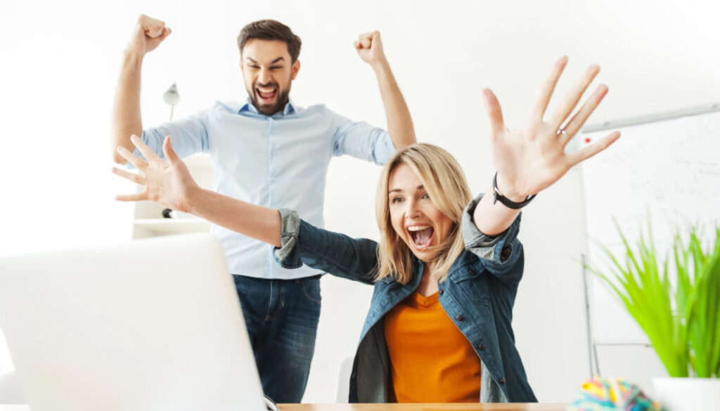 A young blonde woman and a young man discover surprising results on computer with excitement because they are optimizing their linkedin headline