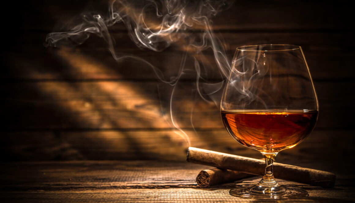 Life insurance Application Rated for Tobacco Use? Lit cigar behind glass of whiskey.