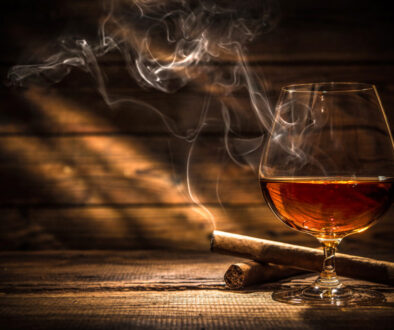 Life insurance Application Rated for Tobacco Use? Lit cigar behind glass of whiskey.
