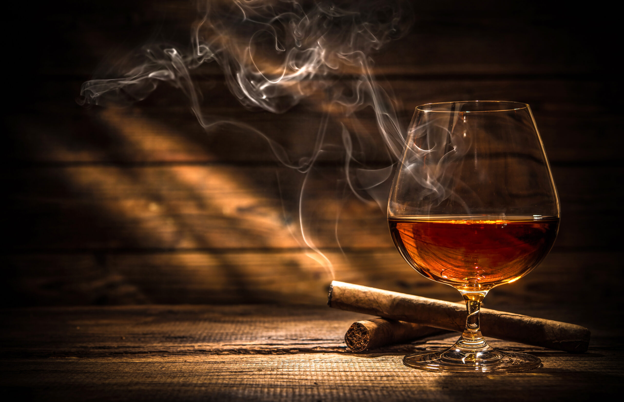Whiskey with smoking cigar Life insurance Application Rated for Tobacco Use? Lit cigar behind glass of whiskey.