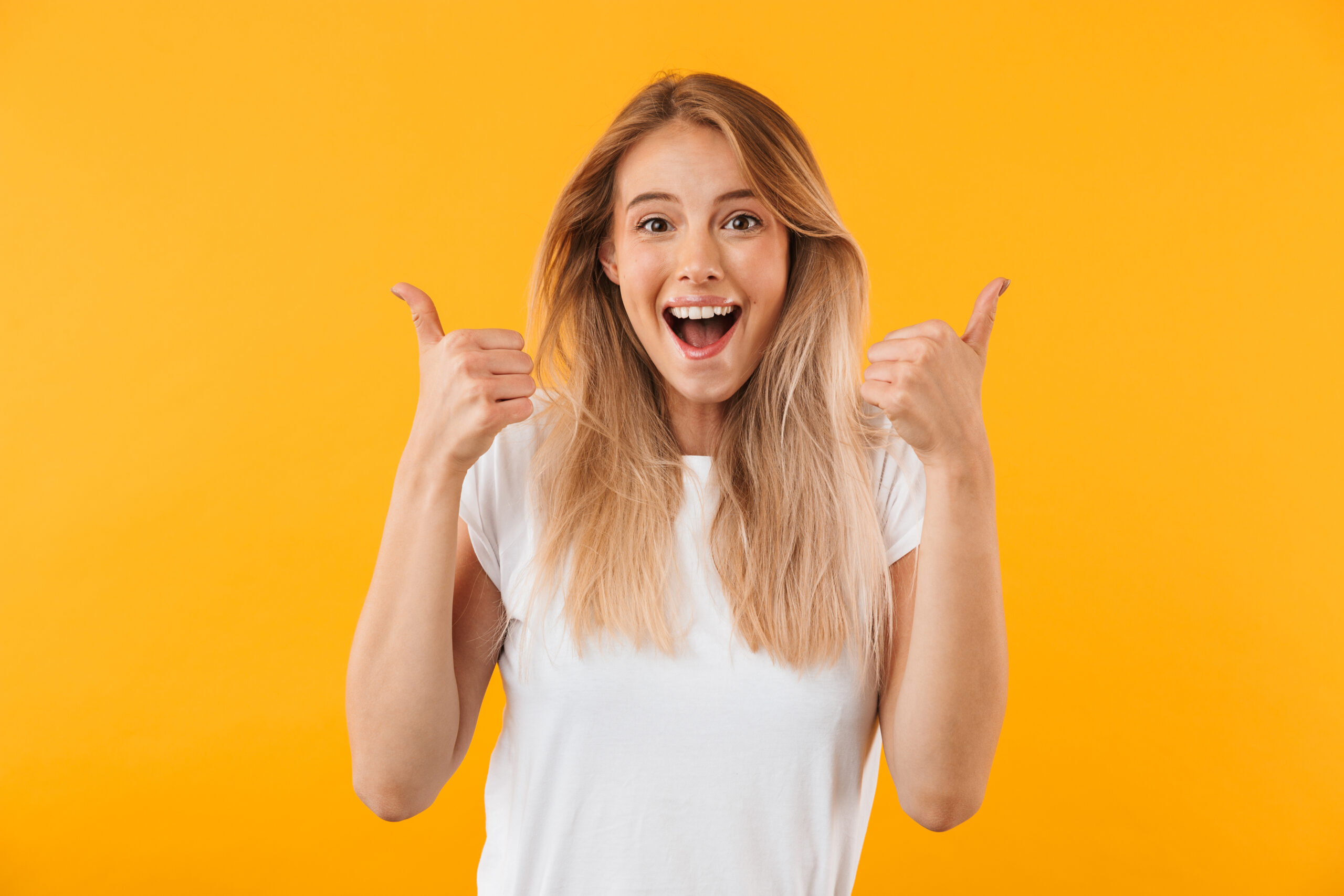 Portrait of an excited young blonde girl Young woman gives two thumbs up