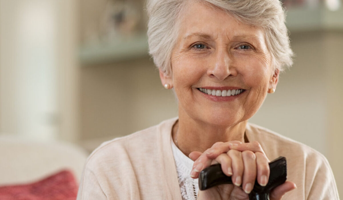 Elderly woman smiling at home Woman with cane with Parkinson's Disease