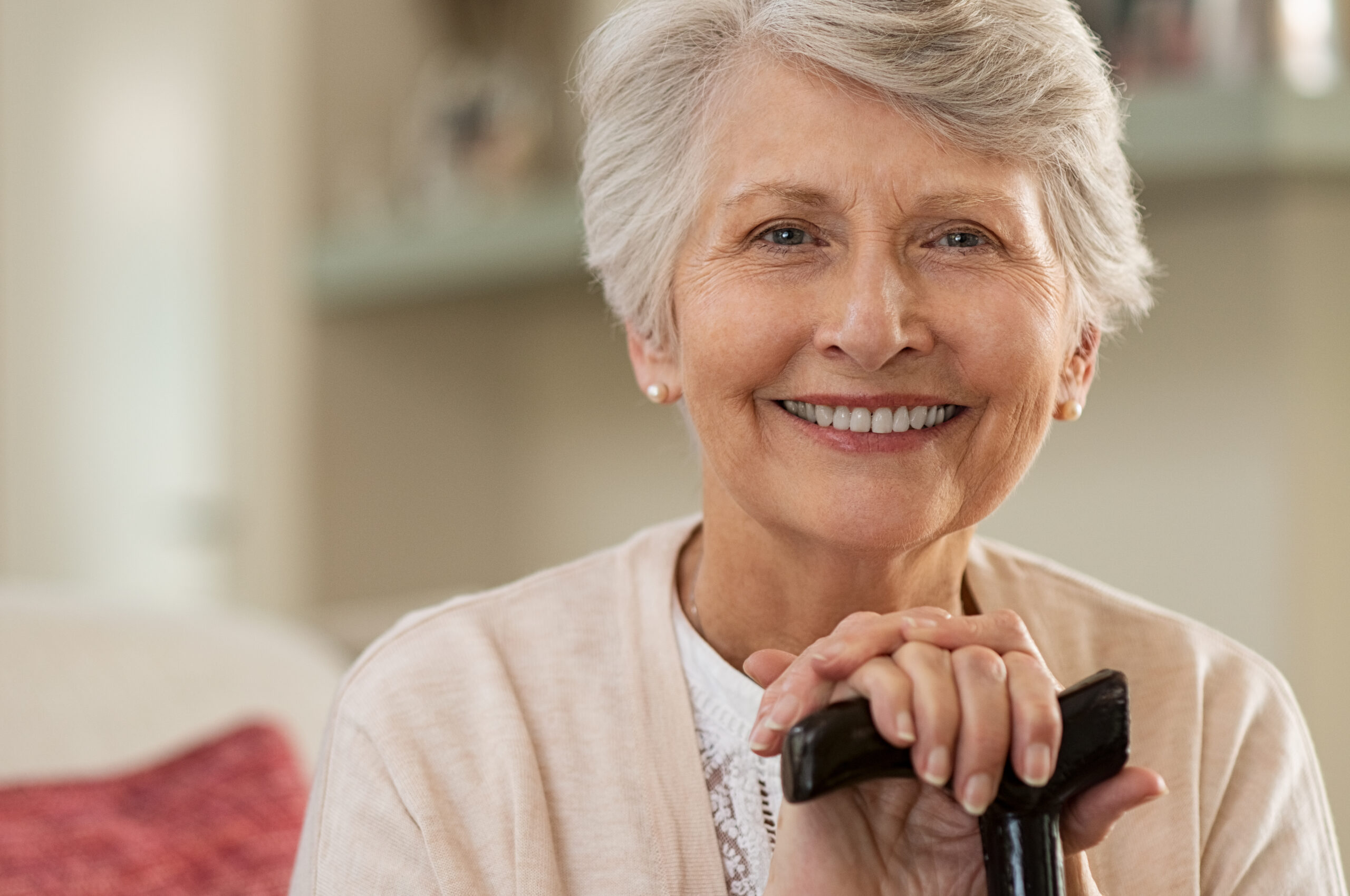 Elderly woman smiling at home Woman with cane with Parkinson's Disease