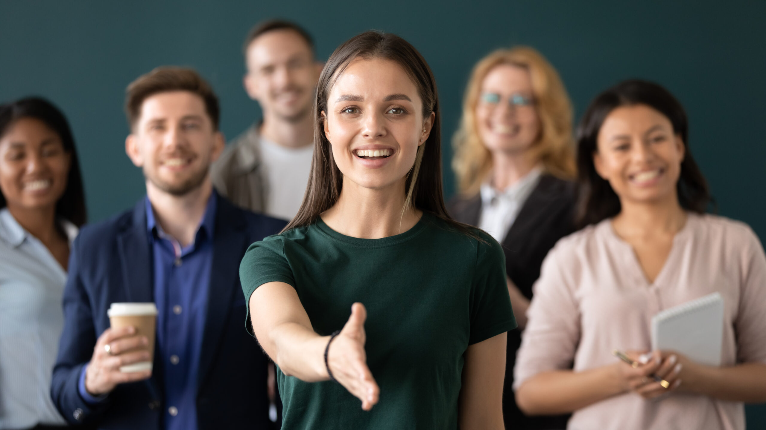 Woman company representative holds out hand for handshake welcoming client Welcome group of young professionals extending a hand