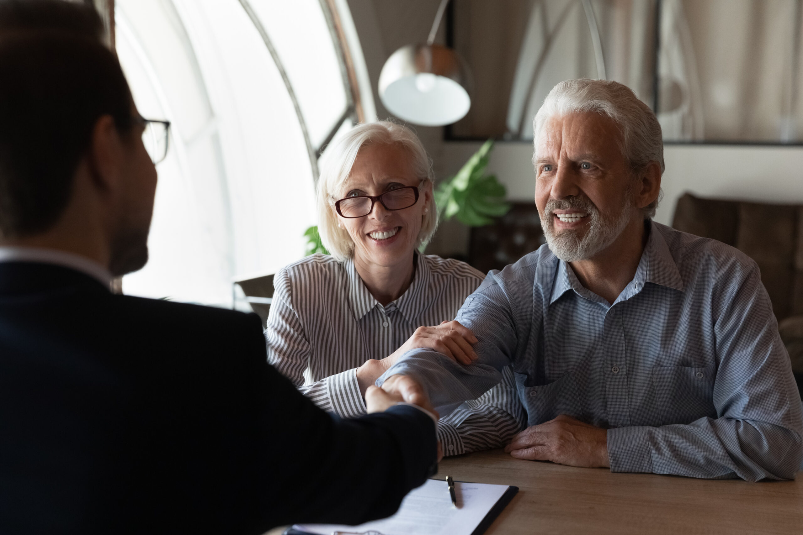 Older business owner shaking hands over a buy-sell agreement