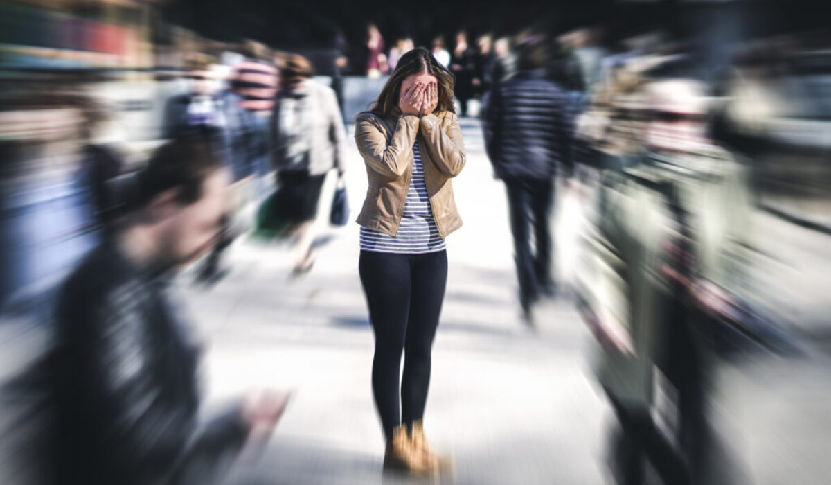 Panic attack in public place. Woman having panic disorder in cit A woman covers her eyes as she is experiencing an anxiety attack in public