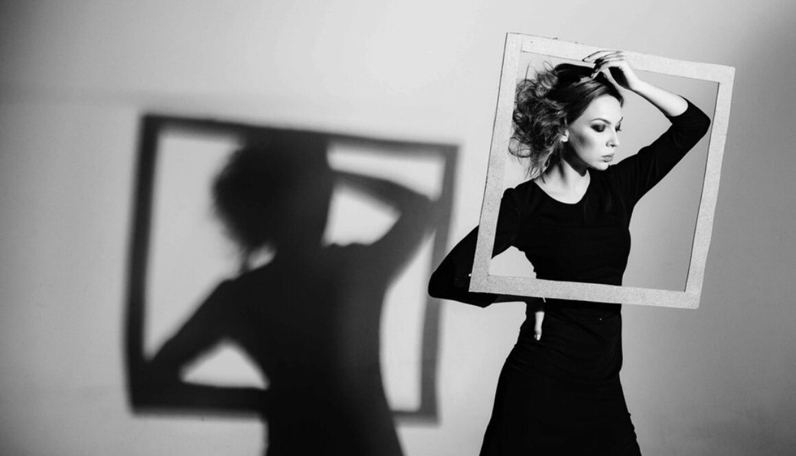 An attractive woman looks through a photo frame she is holding conveying the importance of optimizing your linkedin photo