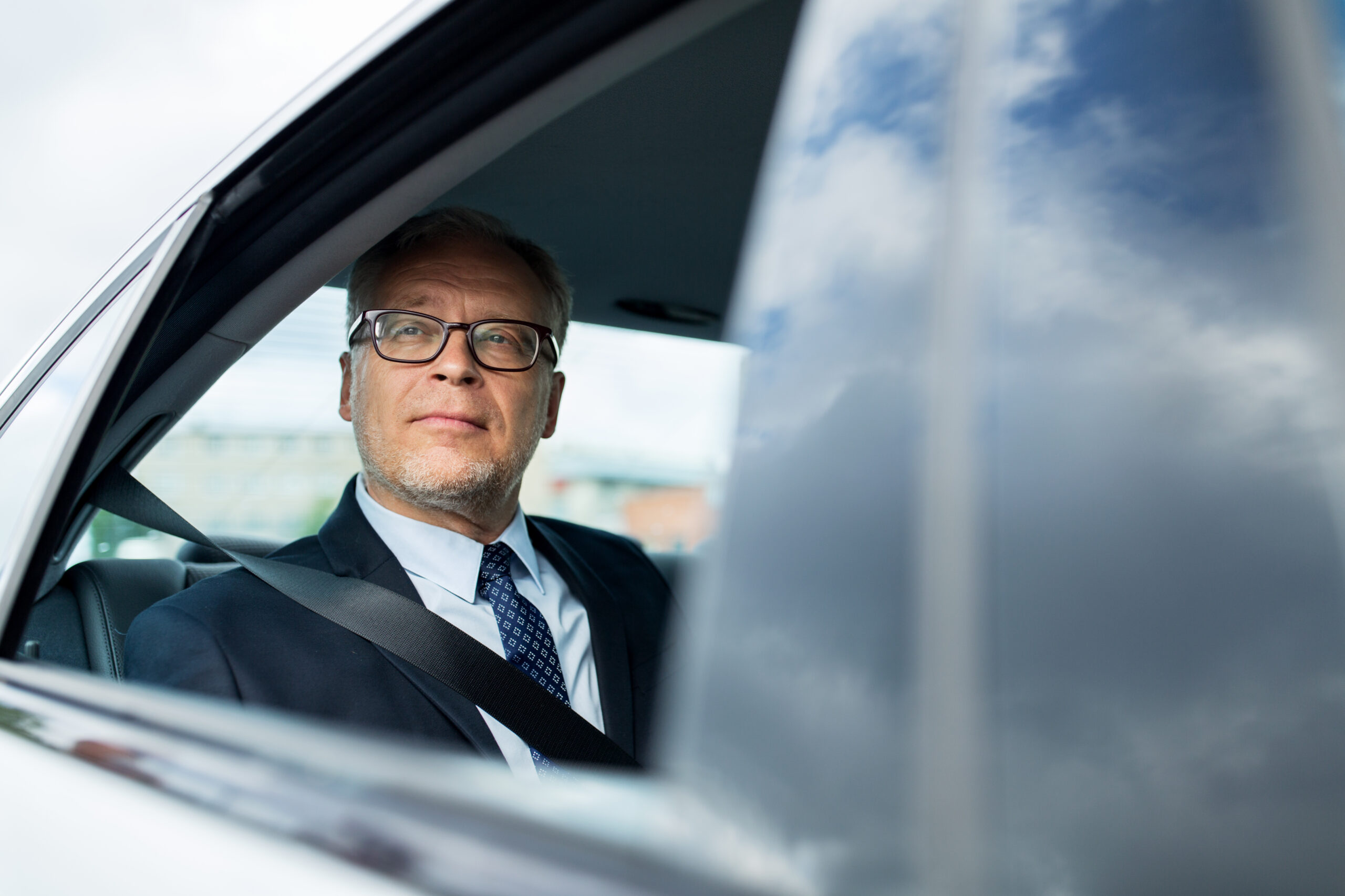 businessman in a car having learned about the potential advantages of layering large life insurance policies